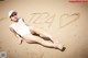 A woman laying on the sand with the word TBA written in the sand.