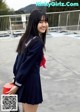 A woman in a school uniform holding a red box.