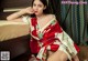 A woman in a red and white kimono sitting on a bed.