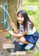 A young woman is holding a hose and smiling.