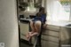 A woman sitting on a stool in a kitchen.