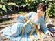 A woman in a blue and yellow dress sitting on the ground.