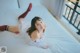 A woman laying on a bed in a white dress and red stockings.