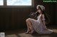 A woman in a pink dress sitting on a wooden floor.