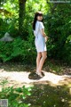 A woman in a blue and white dress standing in the woods.