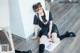 A woman in a school uniform sitting on the floor.