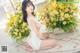 a woman sitting on the floor next to a bunch of flowers