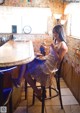 A woman sitting at a table eating a sandwich.