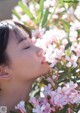 A woman is smelling a bunch of pink flowers.