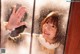 A woman waving her hand in front of a window.