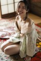 A woman in a kimono sitting on the floor.