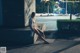 A naked woman sitting on a bench in the middle of a city at night.