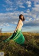 A woman in a long green skirt standing in a field.